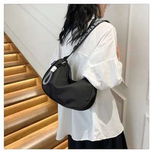 Detail of black crescent shoulder bag with white FASHION & BAG logo printed strap