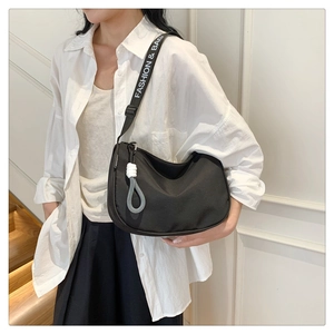 Detail of black nylon crescent bag with wide logo-printed fabric shoulder strap and grey knot charm