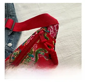 Detail of red floral crossbody bag with phoenix pattern and smooth nylon zipper closure