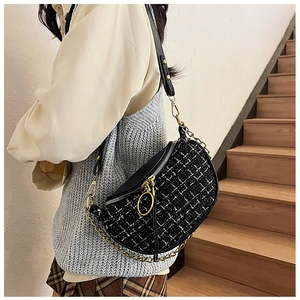 Detail view of the black and white tweed half-moon bag featuring a gold chain and ring zip
