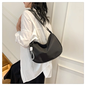 Detail of black crescent shoulder bag with unique fashion charm and wide strap