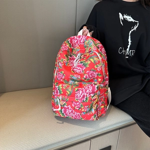 Detail of red floral backpack with traditional Chinese peony pattern on a gray bench