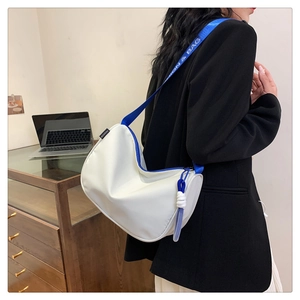 Detail of white crescent bag showing blue strap with ON & BAG text and fashion label