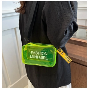 Detail view of neon green PVC jelly bag with fashion mini girl text and wide strap