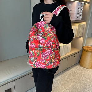 Close-up of canvas backpack featuring traditional red peony floral pattern with sturdy straps
