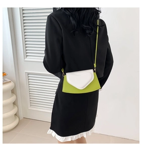 Sac bandoulière moderne vert avocat et blanc porté sur un blazer noir très élégant