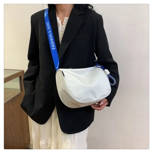 Detail of white crossbody bag with blue fashion logo strap on female model