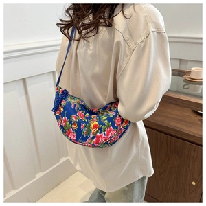 Detail of blue crescent crossbody bag with vibrant peony floral pattern and cord tassel