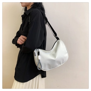 Detail of white nylon hobo bag with black strap and woven knot charm on a model