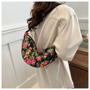 Ethnic floral print crescent crossbody bag with adjustable strap worn by a model