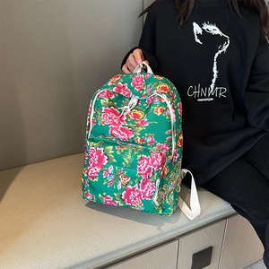Close-up of green floral canvas backpack with pink peony patterns and front zipper pocket