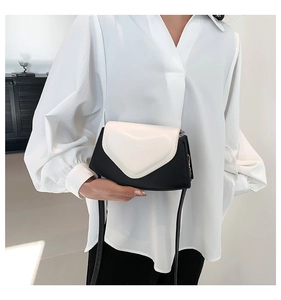 Vue détaillée du sac bandoulière noir et blanc avec un rabat en forme de cœur