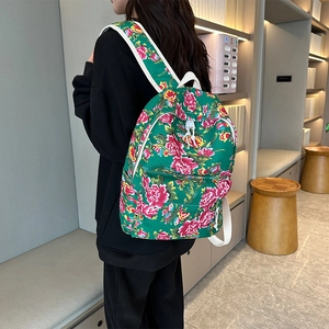 Detail view of ethnic floral backpack in vibrant green canvas with pink flower patterns