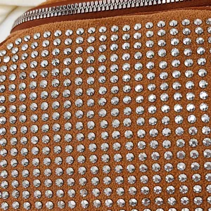 Détail d'un sac en daim marron avec des strass argentés brillants et une fermeture éclair