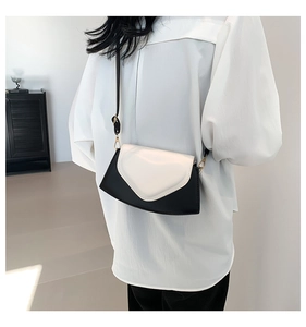 Sac bandoulière minimaliste bicolore noir et blanc avec rabat en cœur sur modèle