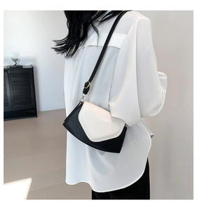 Détail d'un sac à bandoulière bicolore noir et blanc avec boucle en métal doré réglable