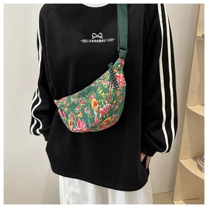 Detail of green floral crossbody bag featuring red blossoms and adjustable strap buckle