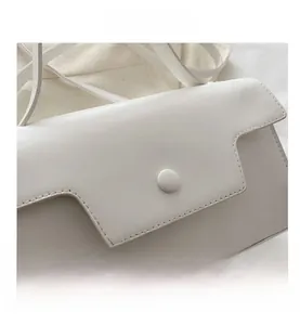 Close-up of white leather handbag detail showing tiered flap edge and magnetic snap button