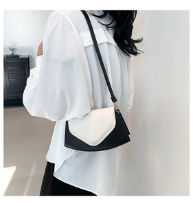 Détail d'un petit sac carré contrasté noir et blanc porté par un mannequin de profil