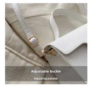 Close-up of golden metal adjustment buckle and white leather shoulder strap of handbag