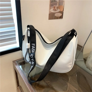 Minimalist white crossbody underarm bag with a fashion logo strap on wooden table