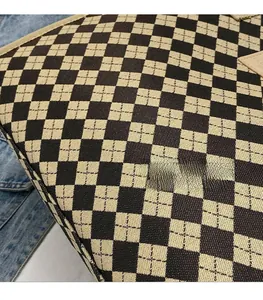Dettaglio della borsa tote a scacchi intrecciata con bordi rinforzati e logo in pelle