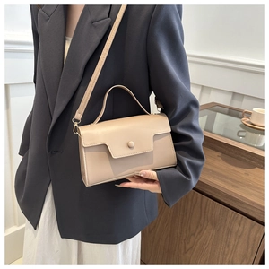 Detailed view of the beige crossbody bag with adjustable strap and top handle on a model