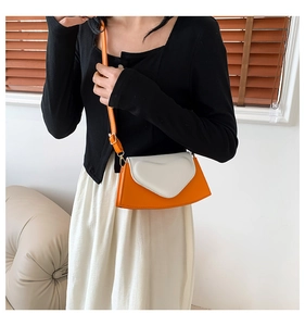 Détail d'un sac bandoulière orange contrasté avec un rabat blanc en forme de cœur en 3D