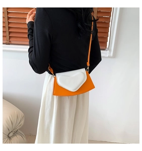 Détail d'un mini sac bandoulière orange avec rabat cœur blanc et boucles dorées sur le modèle