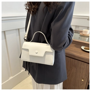 White leather crossbody bag with top handle shown on model in minimalist interior