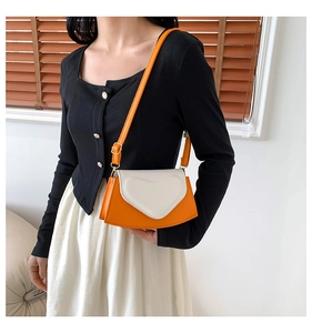 Détail du sac à bandoulière orange avec rabat en forme de cœur et bordure crème contrastée