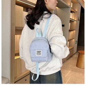 Detail view of light blue corduroy mini backpack with adjustable straps in a bookstore