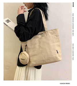 Detail of beige canvas tote bag with side pockets and a small round coin purse attachment