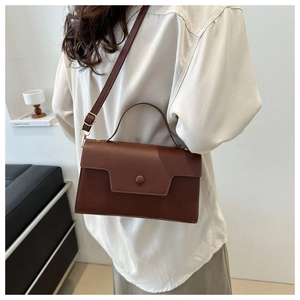 Detail view of a vintage dark brown rectangular crossbody bag with a round buckle accent
