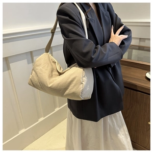 Detailed view of cream canvas crossbody bag with adjustable strap on a female model