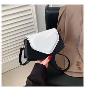 Détail d'un sac bandoulière chic noir et blanc avec boucle cœur 3D sur le rabat