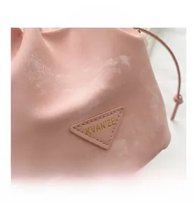 Gros plan d'un sac seau en cuir rose avec logo doré sur un empiècement triangle