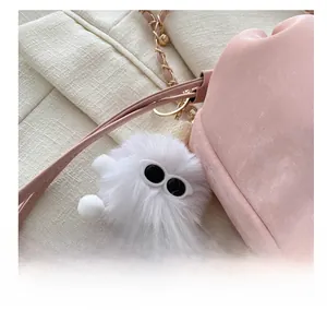 Détail d'un sac seau rose à chaîne avec un joli bijou de sac en peluche blanche douce