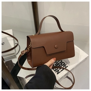 Detailed view of a brown faux leather crossbody bag with gold hardware and top handle