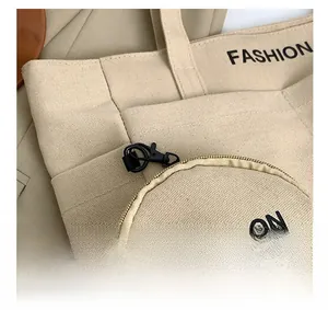 Detail view of beige canvas tote with black fashion print and metallic hook hardware