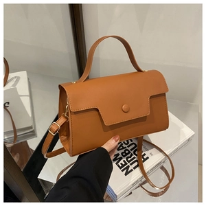 Close-up of caramel leather handbag with vintage buckle and polished gold hardware