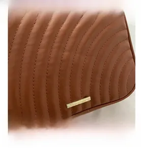 Close-up of caramel brown quilted leather texture with gold metal buckle detail