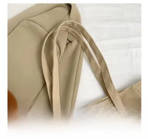 Detail view of the durable canvas handle and fashion lettering on the beige tote bag