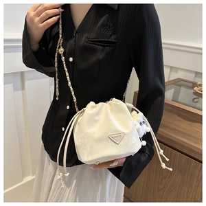 Détail du sac seau crème en cuir nacré avec pendentif en peluche et bandoulière