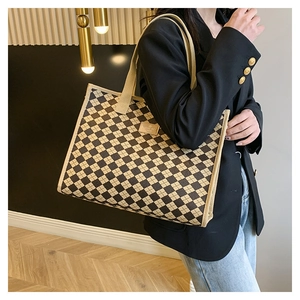 Dettaglio della borsa tote trapuntata con motivo a scacchi beige e manici in tessuto su modella