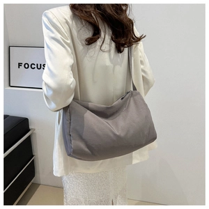 Rear view of a grey large capacity canvas crossbody bag showing fit and drape on model