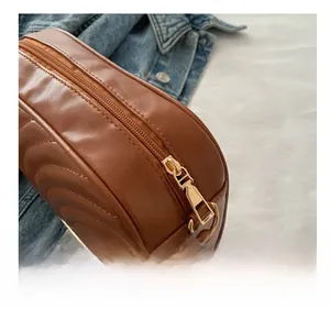 Detail shot of a brown quilted leather crossbody bag with golden zipper and wide strap