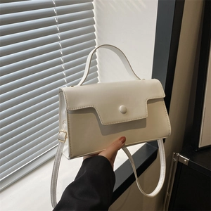 Minimalist white rectangular handbag with geometric flap and circular buckle in soft light