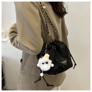 Détail du sac seau noir à cordon avec bandoulière en chaîne dorée et breloque en peluche