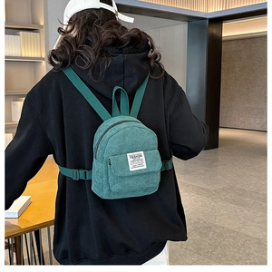 Detail view of mini green corduroy backpack with adjustable straps and fashion label